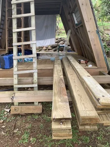 Timber stacked in front of the A-frame before the build